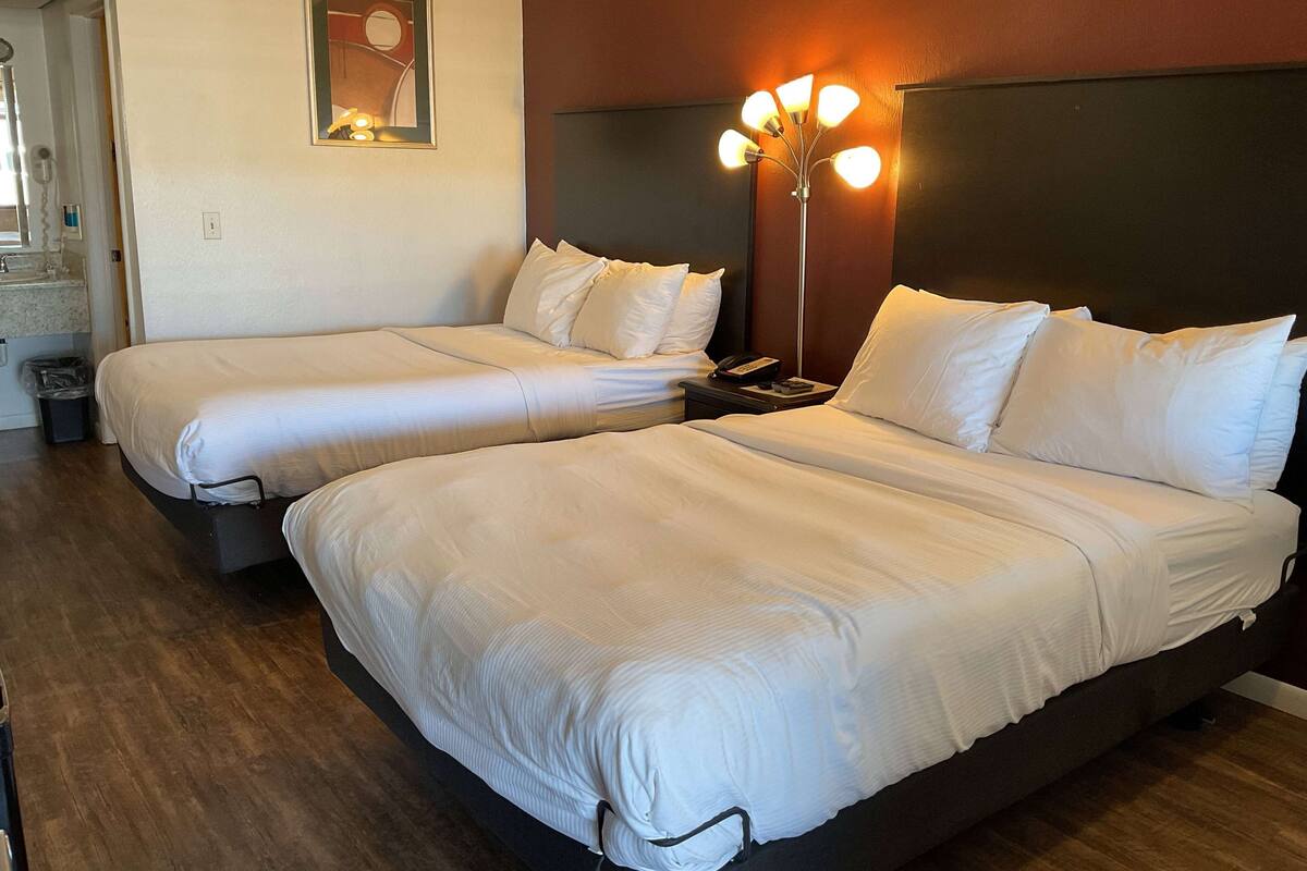 A hotel room with two single beds, a bedside table with a lamp, and a mirror on the wall.