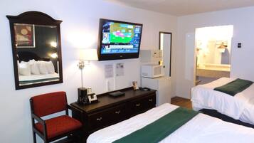 Hotelkamer met twee bedden, een aan de muur bevestigde televisie, een bureau met lamp, een stoel en een spiegel.