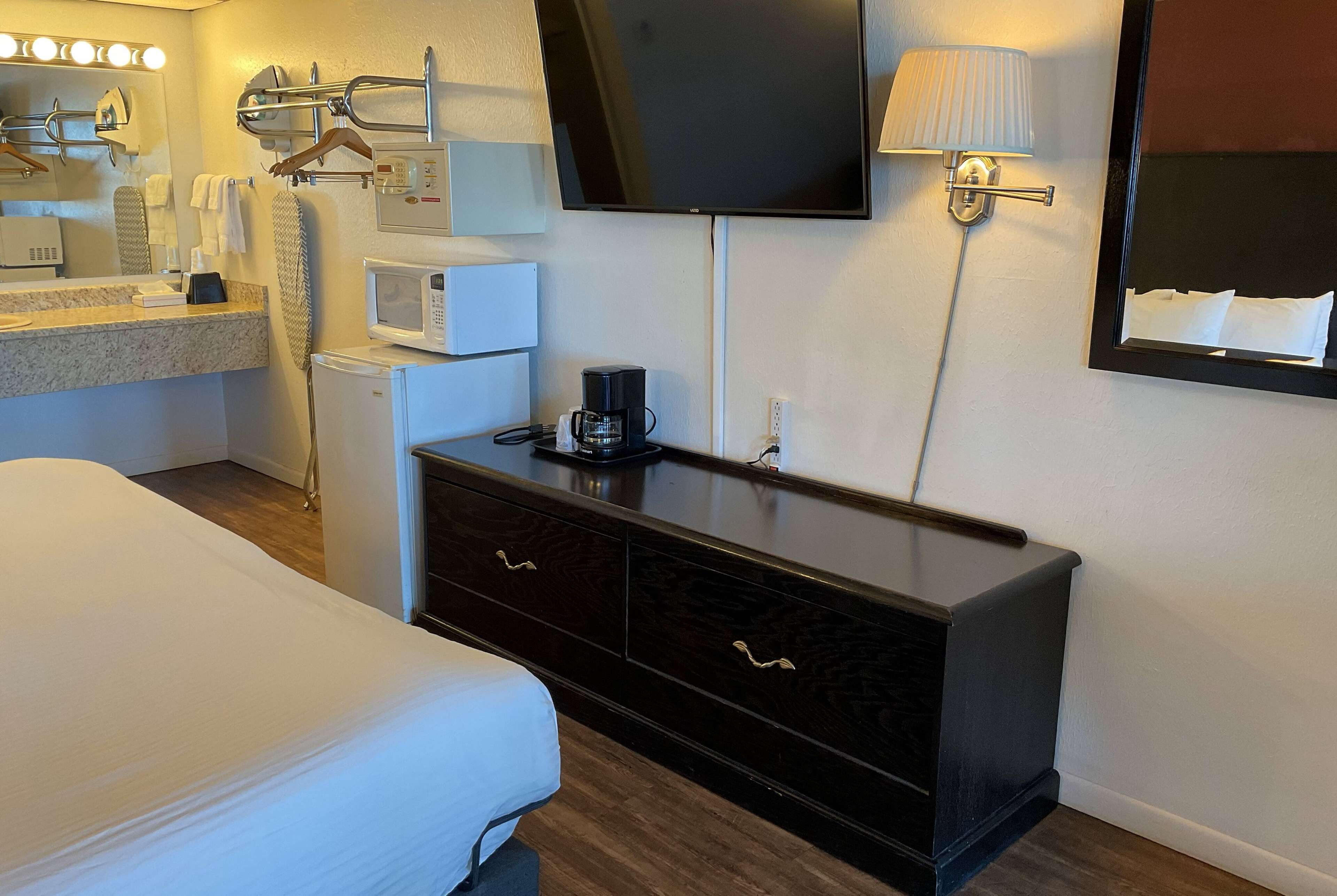 A hotel room with a bed, a dresser, a TV, a microwave, and a coffee maker.