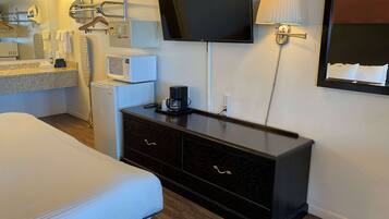 A hotel room with a bed, a dresser, a TV, a microwave, and a coffee maker.