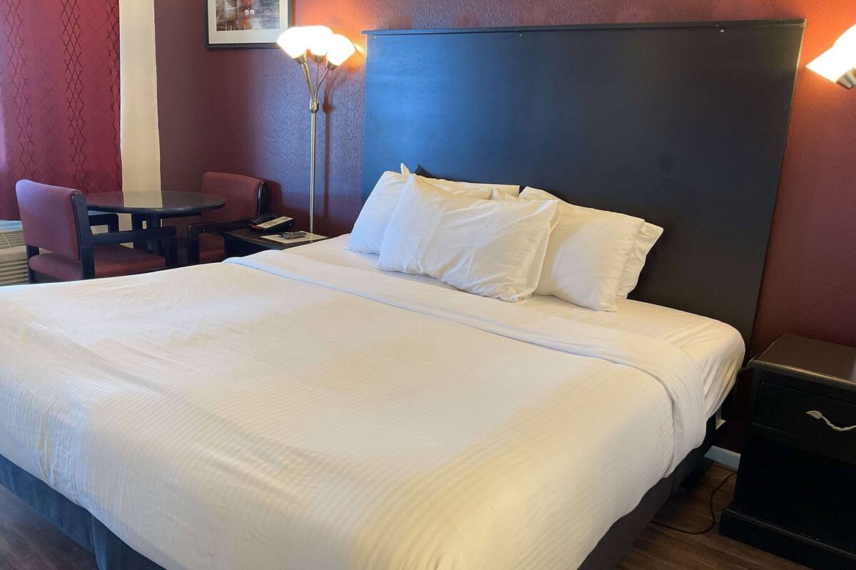 A hotel room with a large bed, a desk, and a chair.