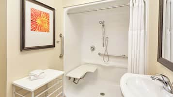 A bathroom with a shower, a sink, a towel rack, and a framed picture on the wall.