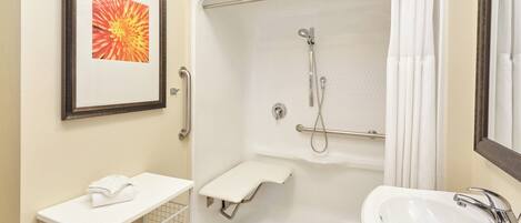 A bathroom with a shower, a sink, a towel rack, and a framed picture on the wall.