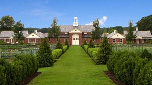 A large, symmetrical building with a central entrance, flanked by two wings, and surrounded by well-maintained lawns and hedges.