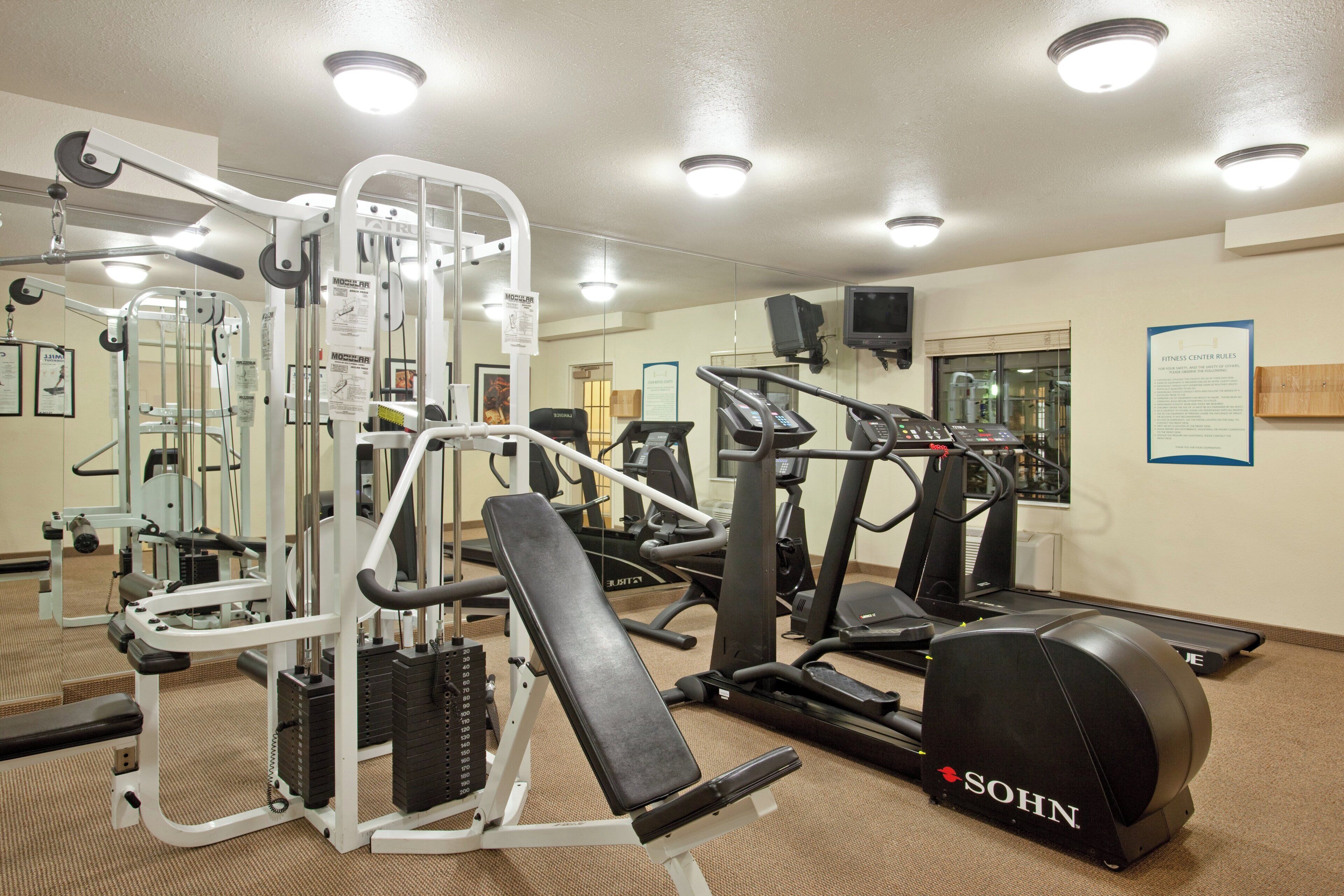 Un centre de remise en forme équipé de divers appareils d’exercice, notamment des tapis de course, un banc de musculation et une machine à câbles.