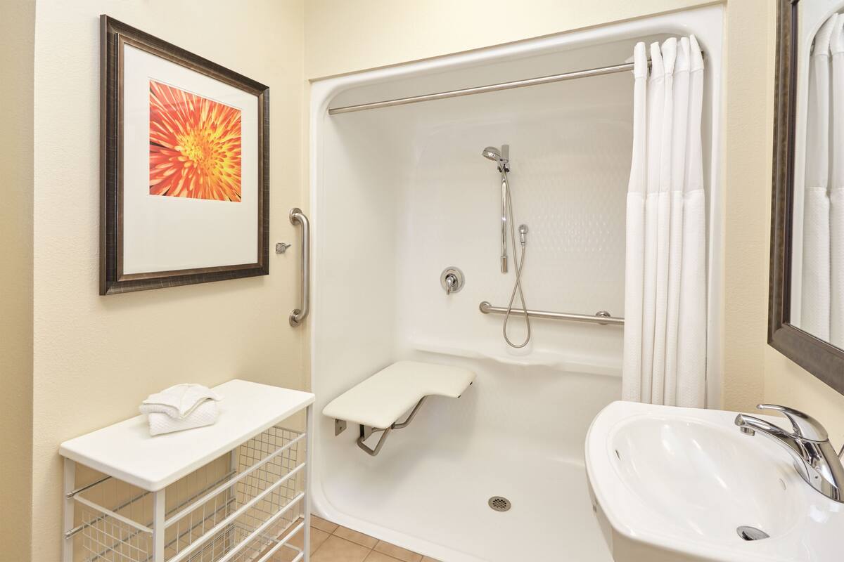A bathroom with a shower, sink, and a framed picture on the wall.