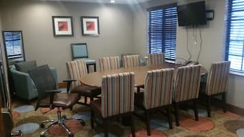 A conference room with a round table, striped chairs, a sofa, and a TV on the wall.