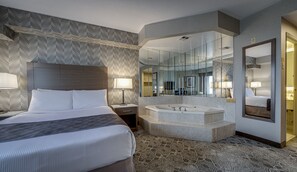 A hotel room with a large bed, a separate bathroom with a bathtub, and a large mirror.
