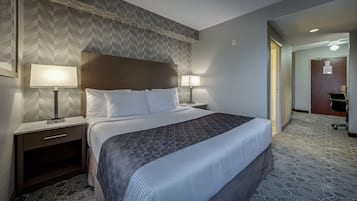 A hotel room with a large bed, two bedside lamps, a wooden headboard, and a patterned carpet.