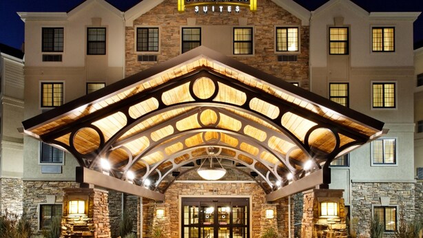 Staybridge Suites hotel with a stone facade, a covered entrance, and a sign above the entrance. - Staybridge Suites Chicago - Glenview by IHG (Glenview)