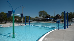 A swimming pool with clear blue water, a diving board, and a lifeguard stand. - Staybridge Suites Chicago - Glenview by IHG (Glenview)