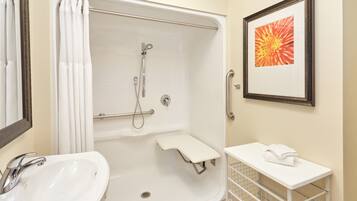A bathroom with a bathtub, a sink, a shower, a framed picture, and a towel rack.