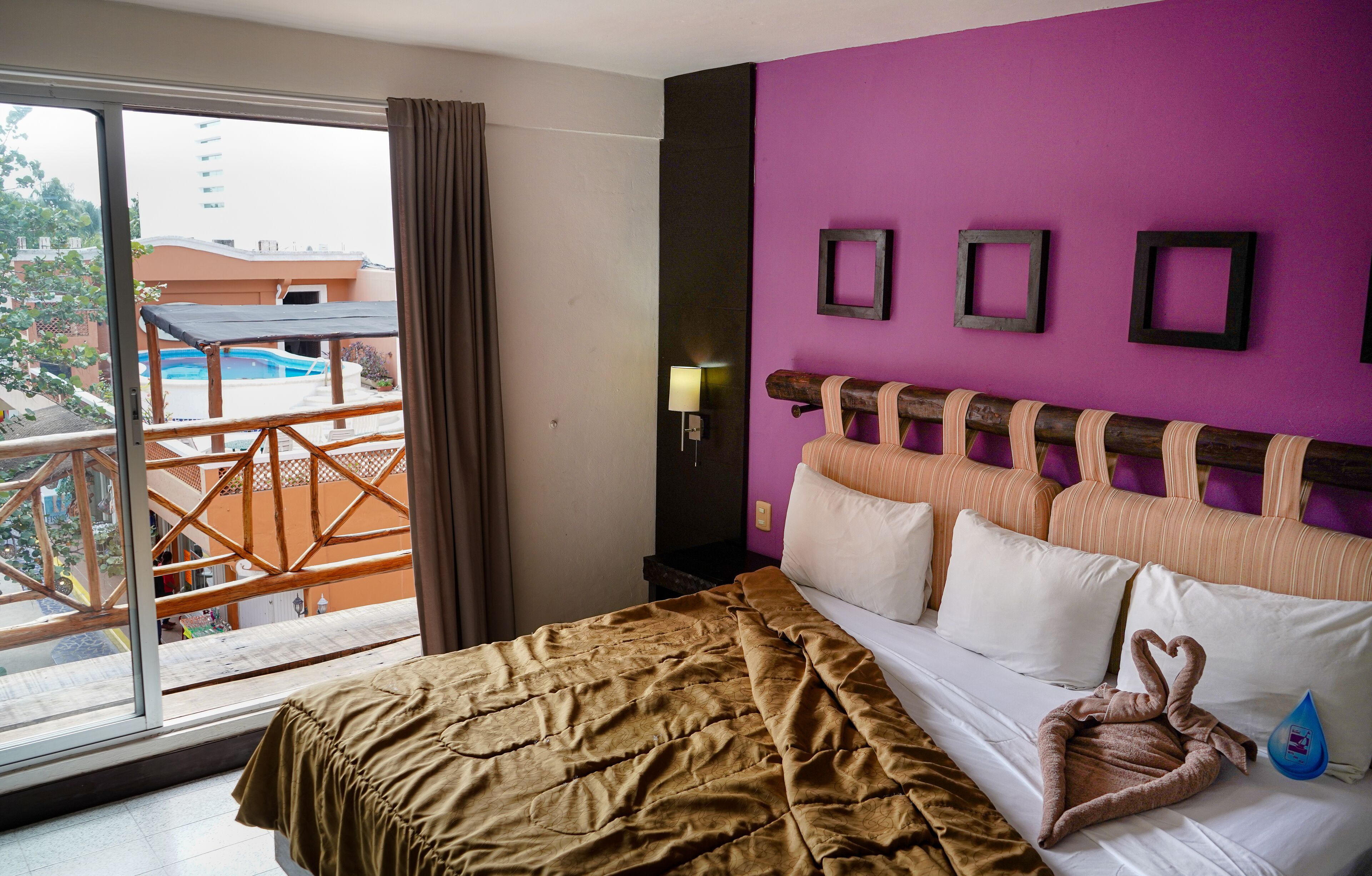 Une chambre d’hôtel avec un lit, un balcon et une vue sur une piscine.