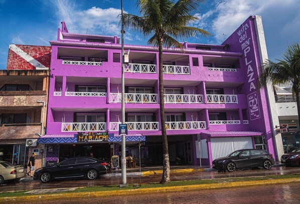 Un edificio de varios pisos con balcones, un cartel que dice 'Vista del Mar Plaza' y una señalización de 'Hotel'.