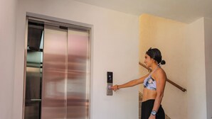Una persona usando un ascensor en un edificio con una escalera cerca.