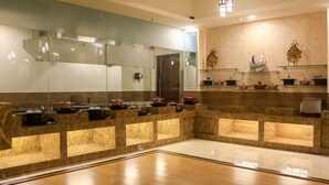 A modern kitchen with marble countertops, a large mirror, and a variety of cookware on shelves. - Dee Marks Hotel & Resorts (New Delhi)