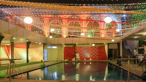 A pool area with a covered deck, string lights, and a red curtain backdrop. - Dee Marks Hotel & Resorts (New Delhi)