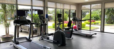 Un gimnasio con cintas de correr, elípticas y una bicicleta estática.