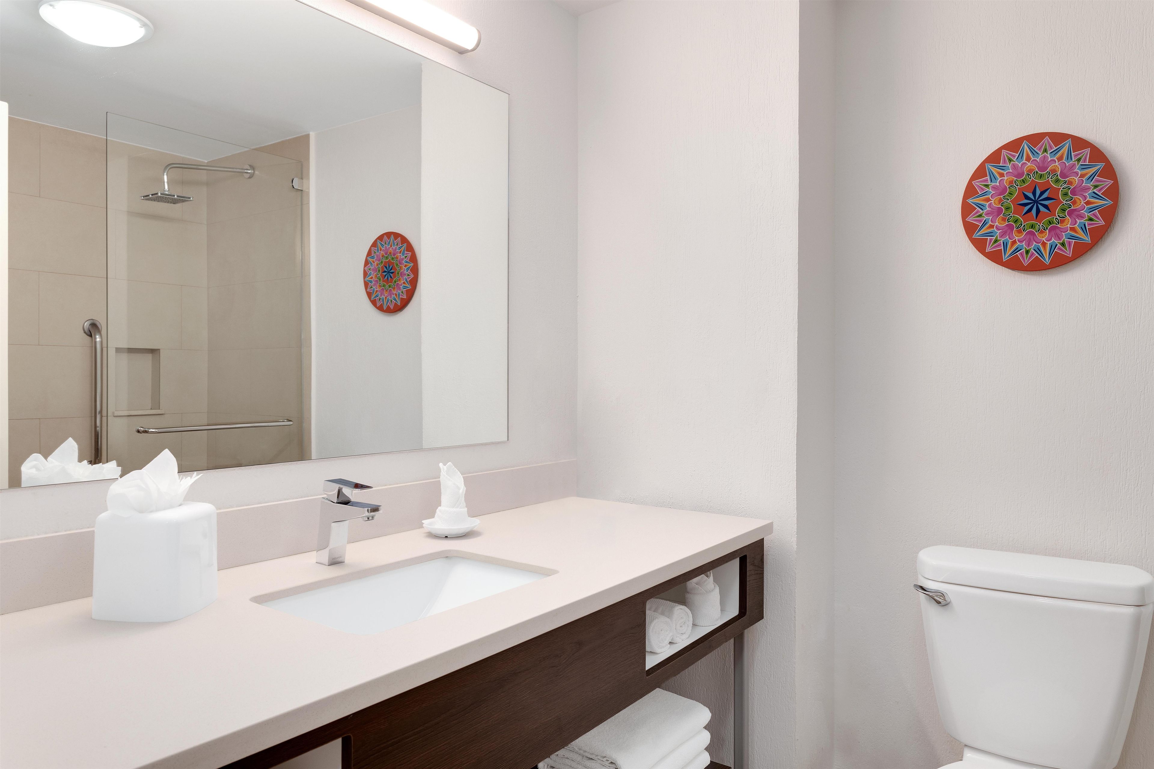 A modern bathroom with a large mirror, a sink, and a toilet.