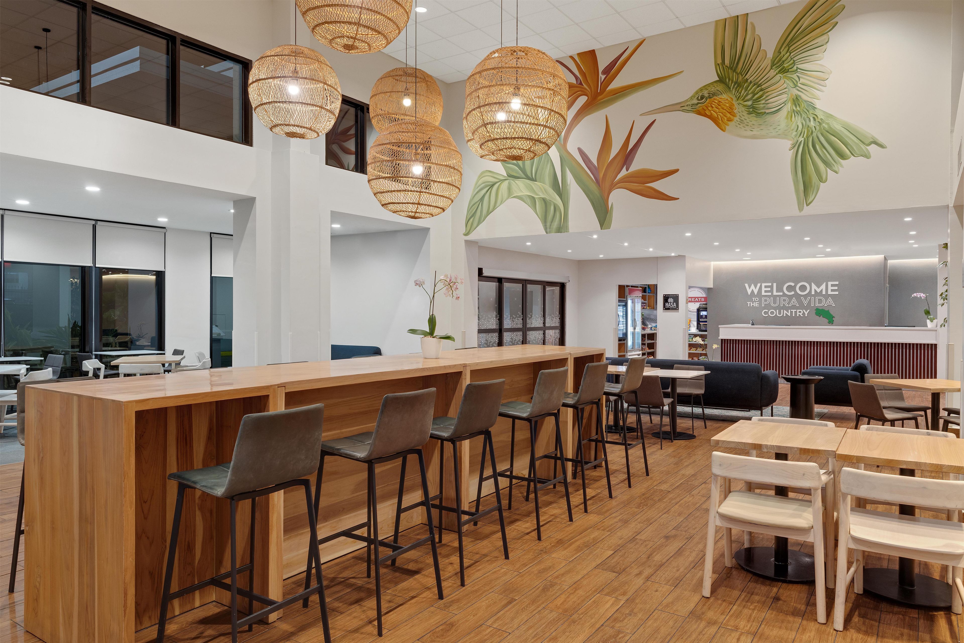 A modern interior with a wooden bar area, seating, and a mural of a hummingbird.