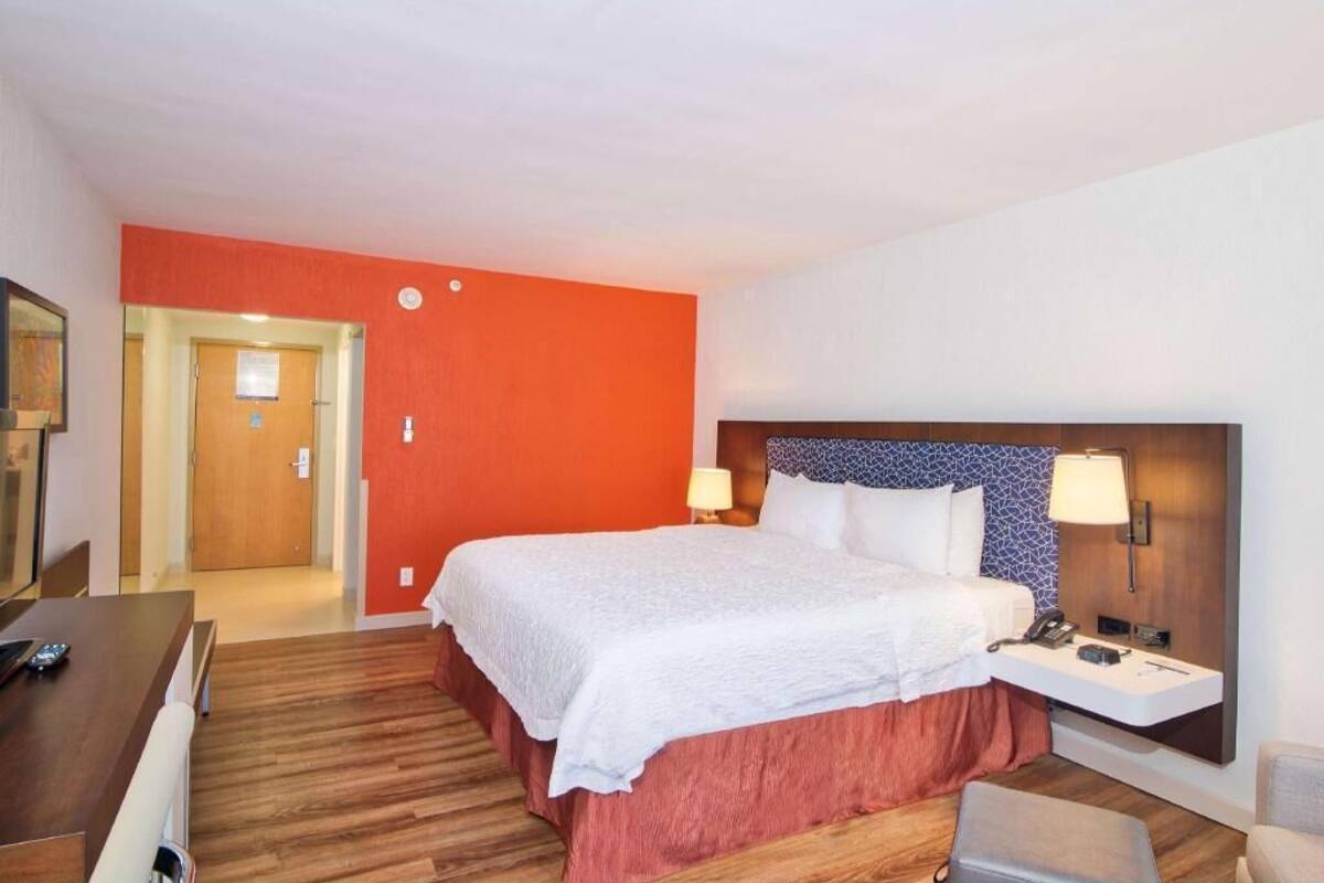 Ein Hotelzimmer mit Bett, Nachttischen, einem Schreibtisch und einem Stuhl.