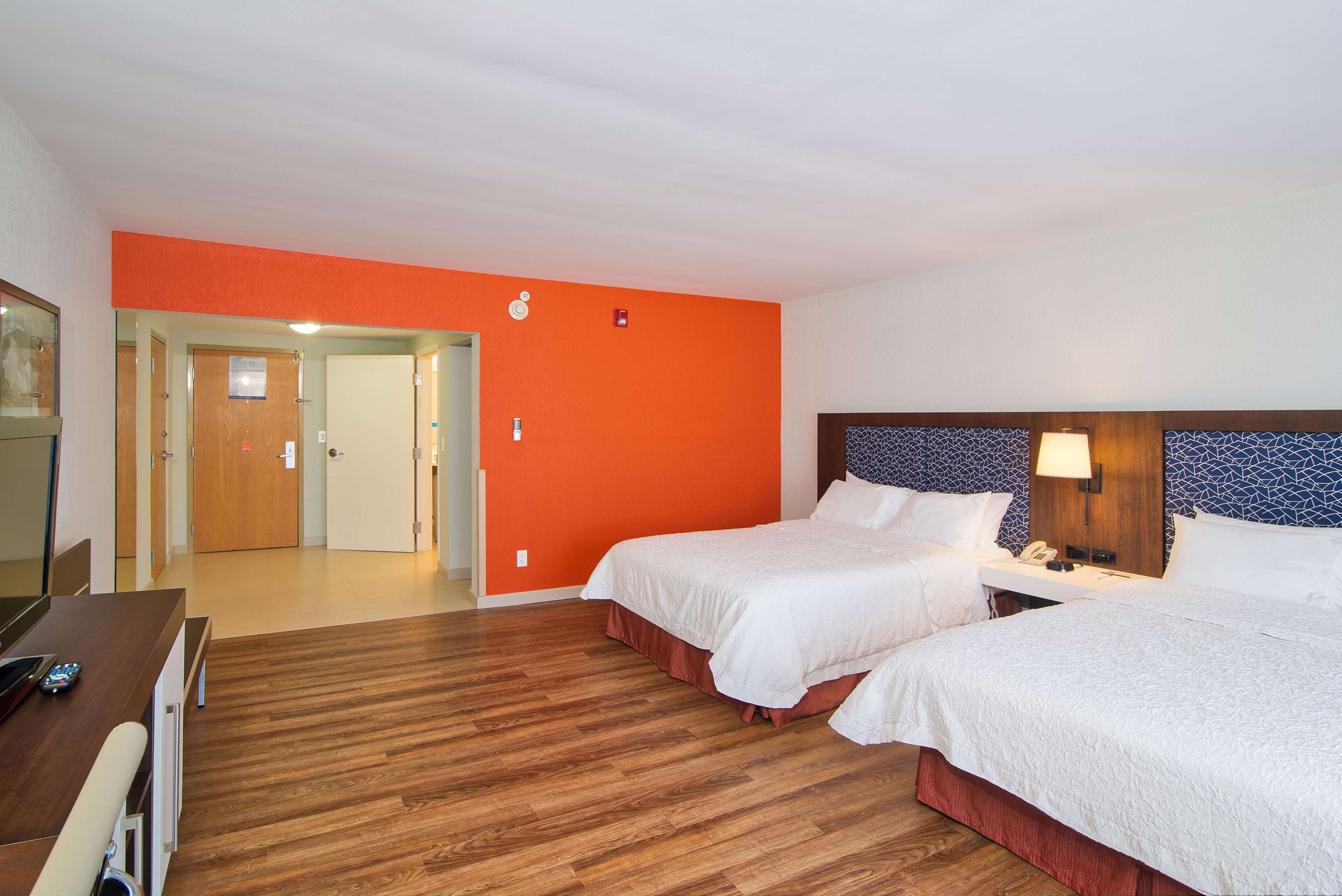 Habitación de hotel con dos camas, un escritorio y suelo de madera.