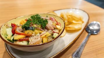 Un tazón de ensalada con diferentes verduras y una cuchara sobre una mesa.