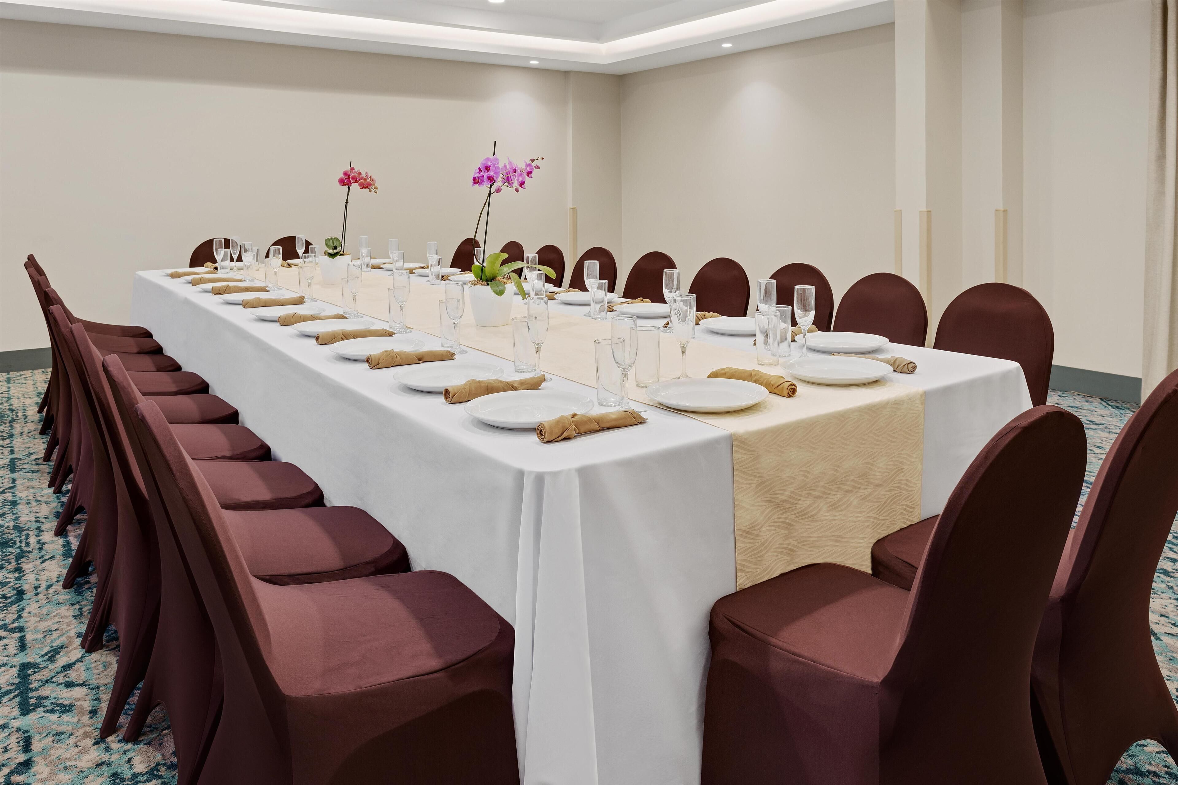 A long conference table with chairs, glassware, plates, and napkins set for a meeting.
