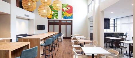 A spacious restaurant with high ceilings, wooden tables and chairs, and hanging wicker lamps.