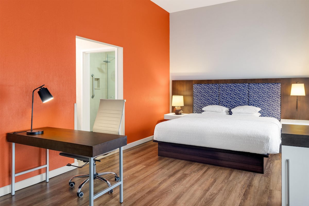 Ein Hotelzimmer mit einem Bett, Nachttischlampen, einem Schreibtisch und einem Stuhl.