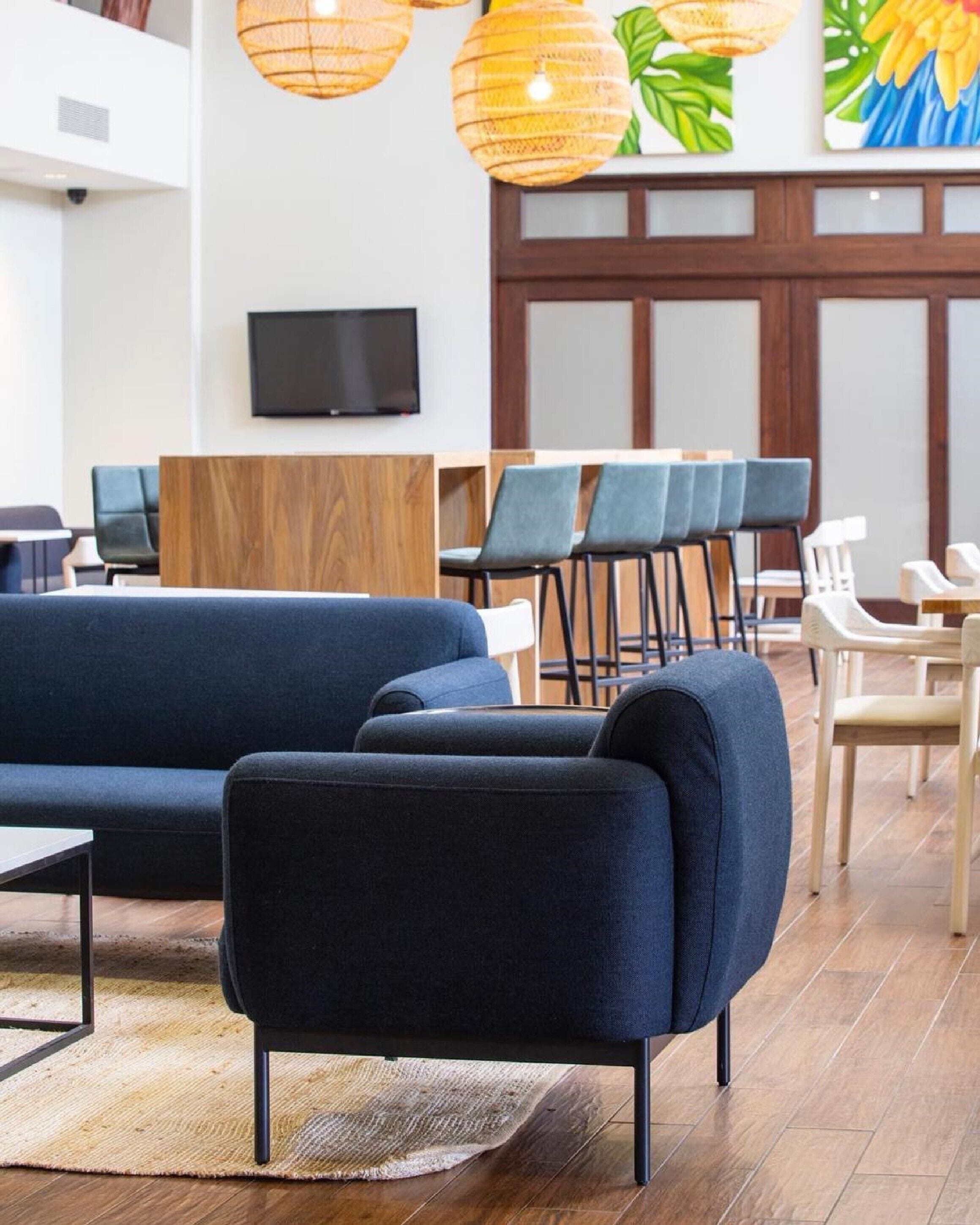 A modern lounge area with a blue sofa, wooden panel wall, and a flat-screen TV.