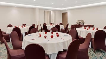 Un salón de conferencias con mesas redondas, sillas y una parrilla.
