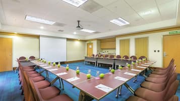 Ein Konferenzraum mit einem langen Tisch, Stühlen, einer Projektionsleinwand und einem Schild mit der Aufschrift 'SALIDA'.