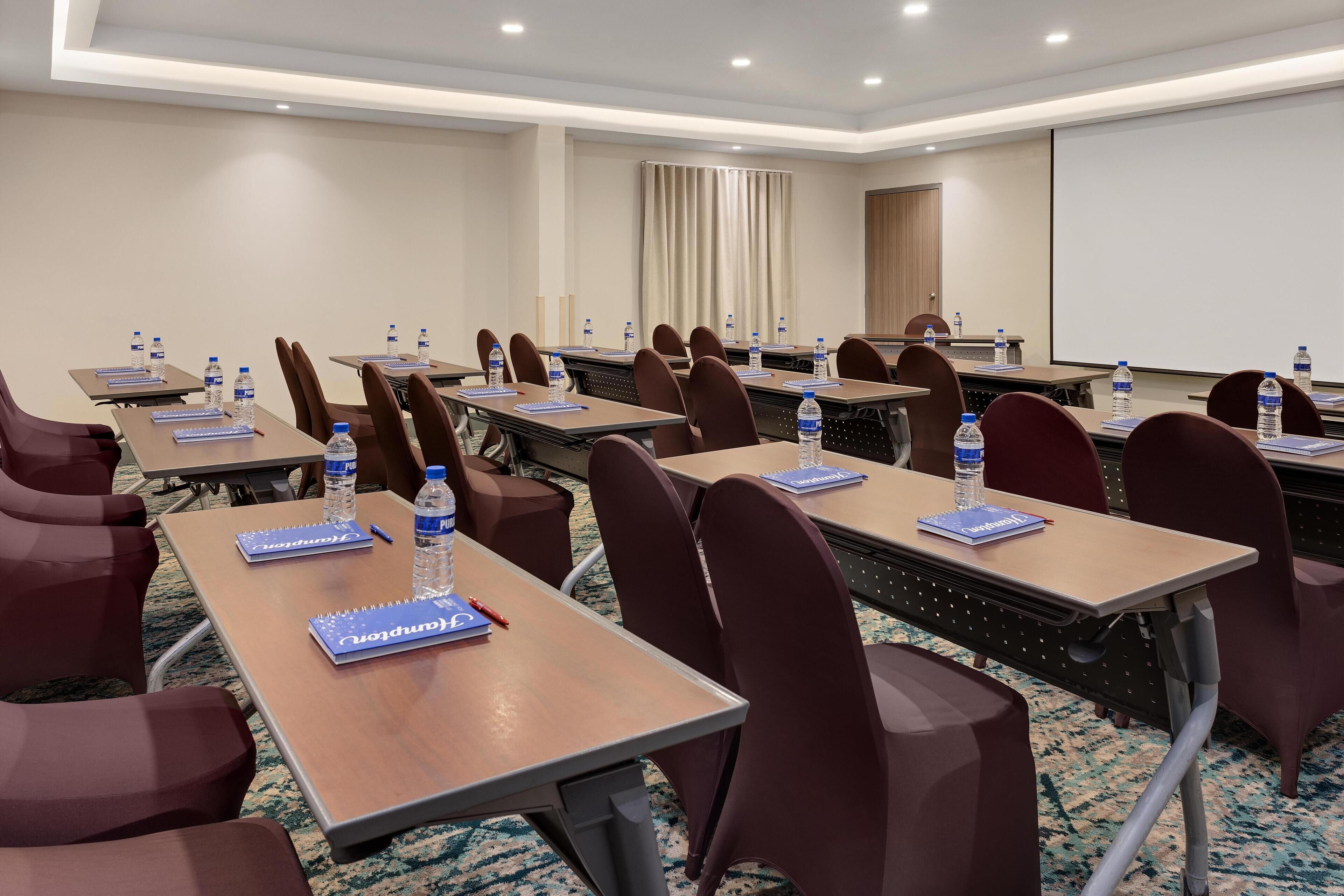 A conference room with multiple tables, chairs, water bottles, and nameplates.