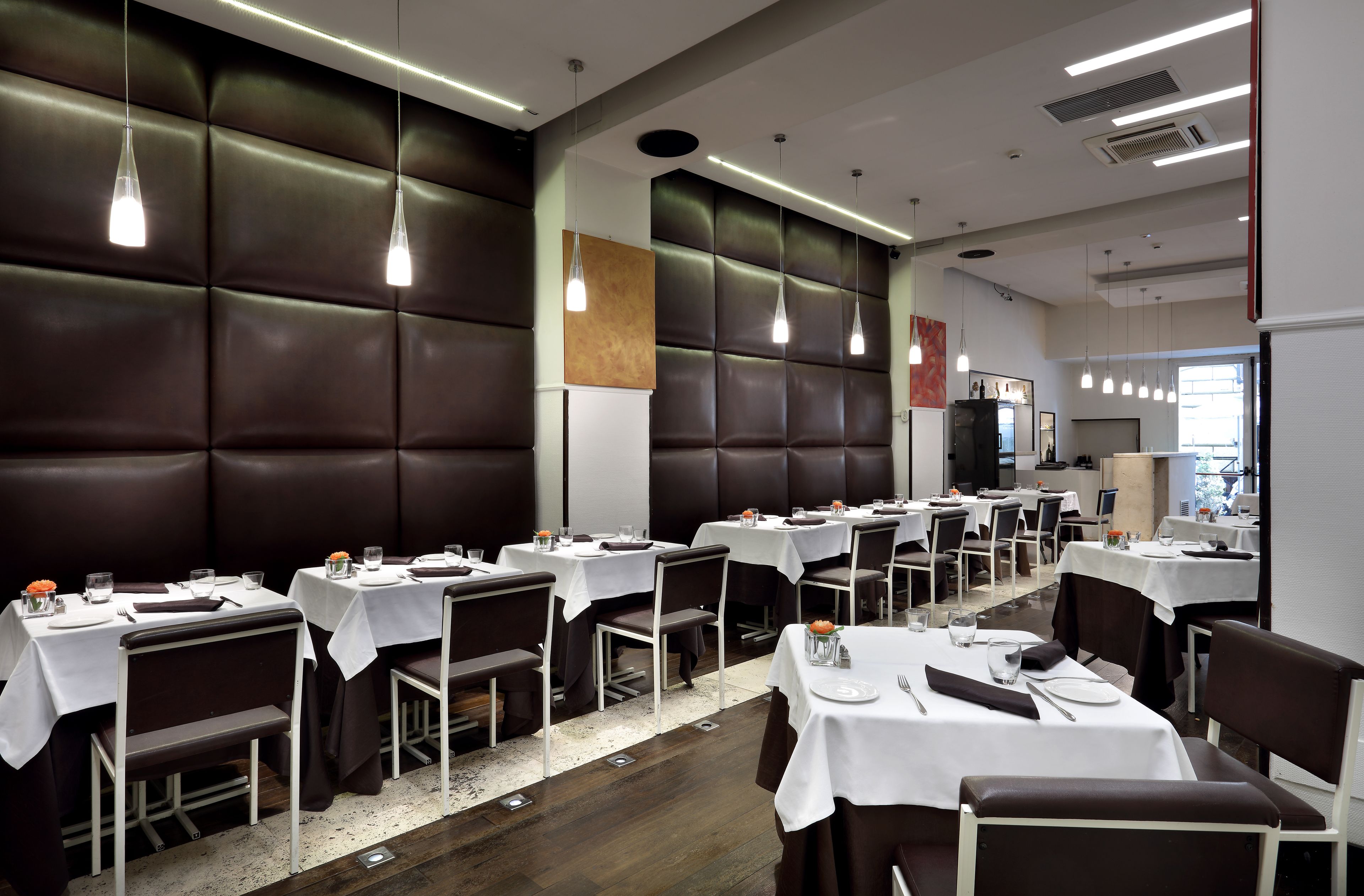 A restaurant with booths and tables, modern lighting, and a clean, contemporary design.