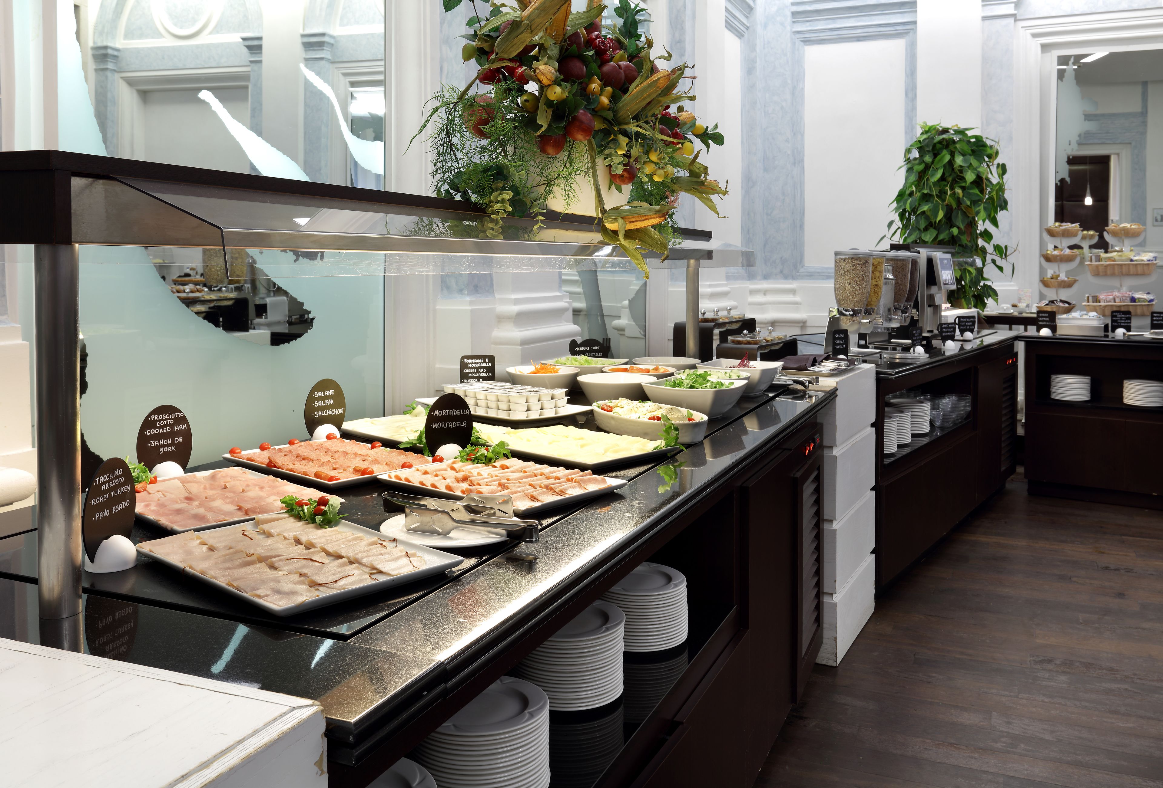 A buffet with various food options, including salads, meats, and desserts, displayed on a counter with a glass enclosure.