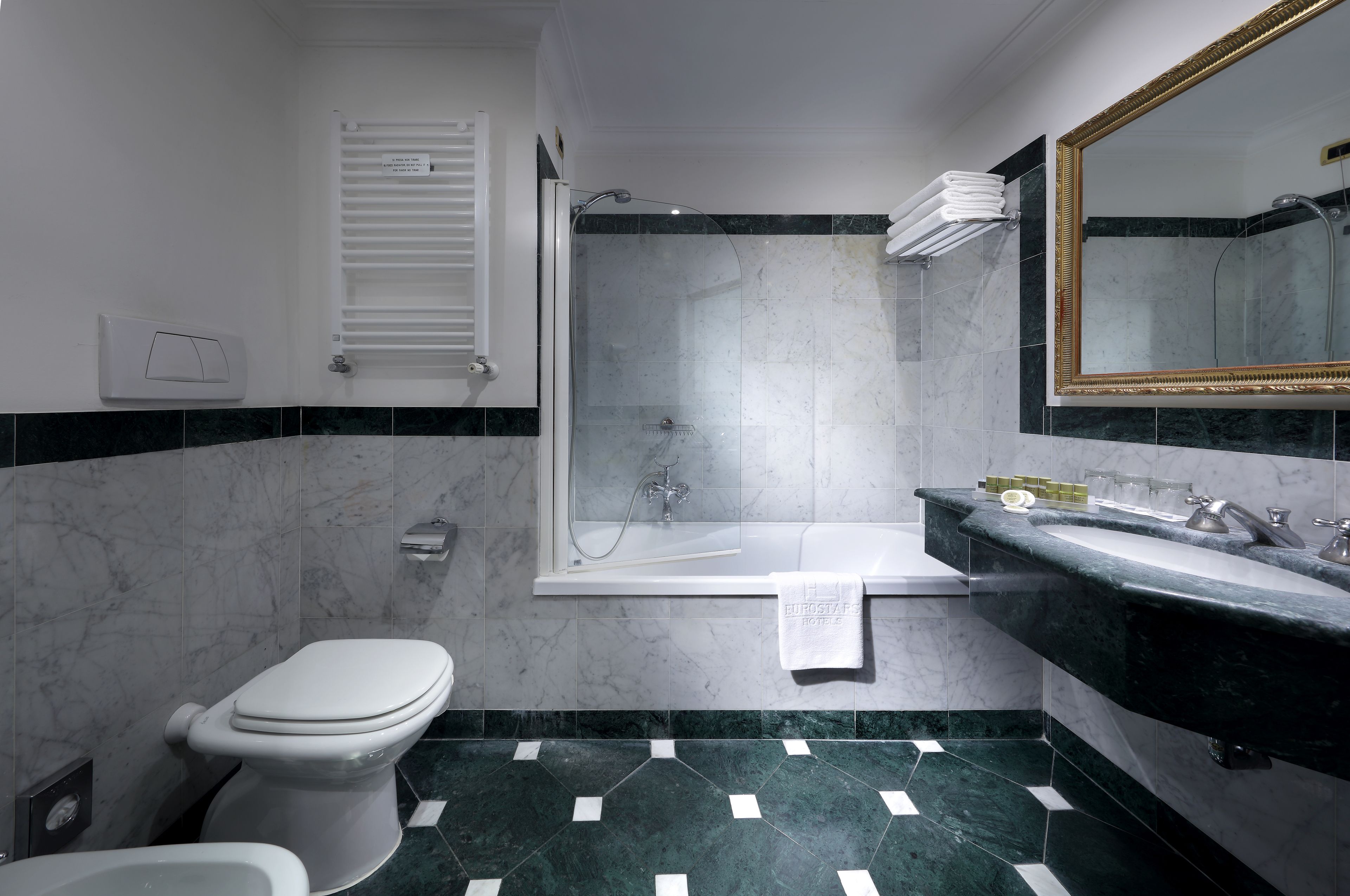 A bathroom with a toilet, shower, and sink.