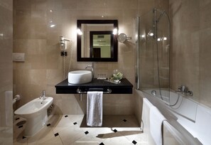 A modern bathroom with a bidet, a sink, a mirror, and a shower.