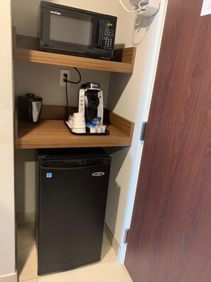 Une petite cuisine équipée d’un four à micro-ondes, d’une machine à café et d’un réfrigérateur.