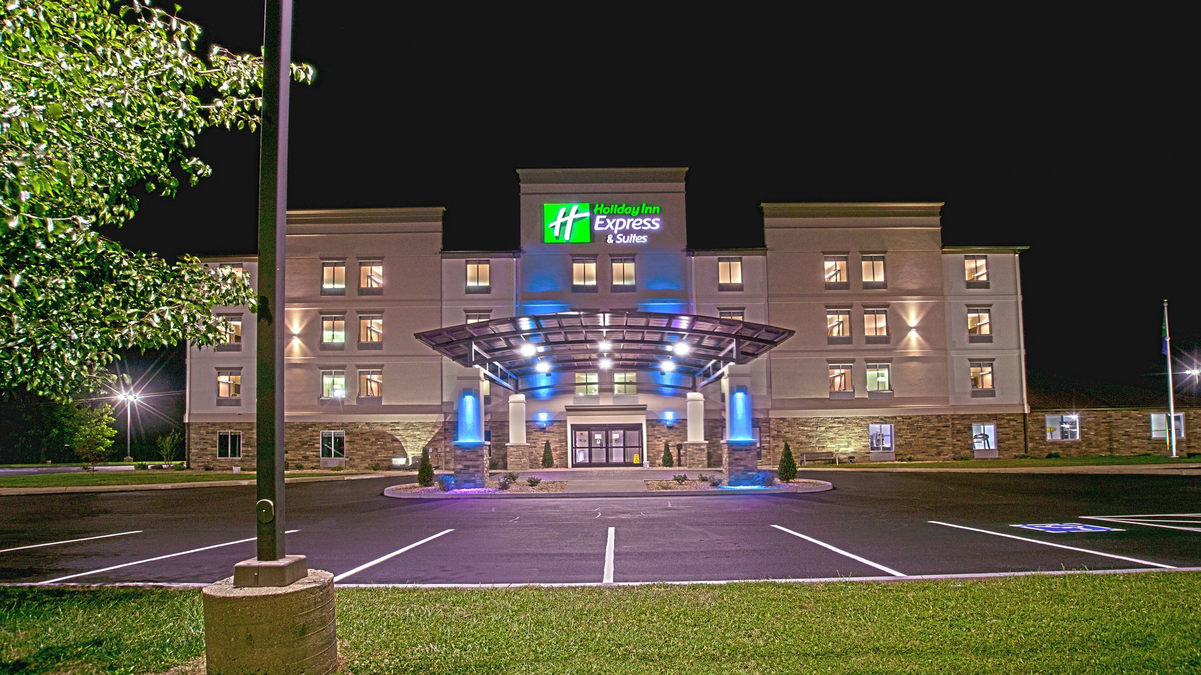 A Holiday Inn Express & Suites hotel with a covered entrance, parking lot, and a well-lit facade.