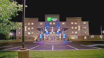 A Holiday Inn Express & Suites hotel with a covered entrance, parking lot, and a well-lit facade.