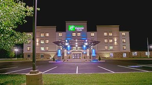 Ein Holiday Inn Express & Suites Hotel mit überdachter Eingangspartie, Parkplatz und gut beleuchteter Fassade.