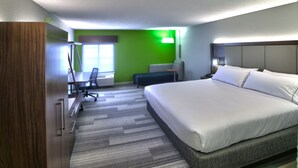 Une chambre d’hôtel avec un grand lit, un bureau avec une chaise, une petite table, un canapé et un mur vert.