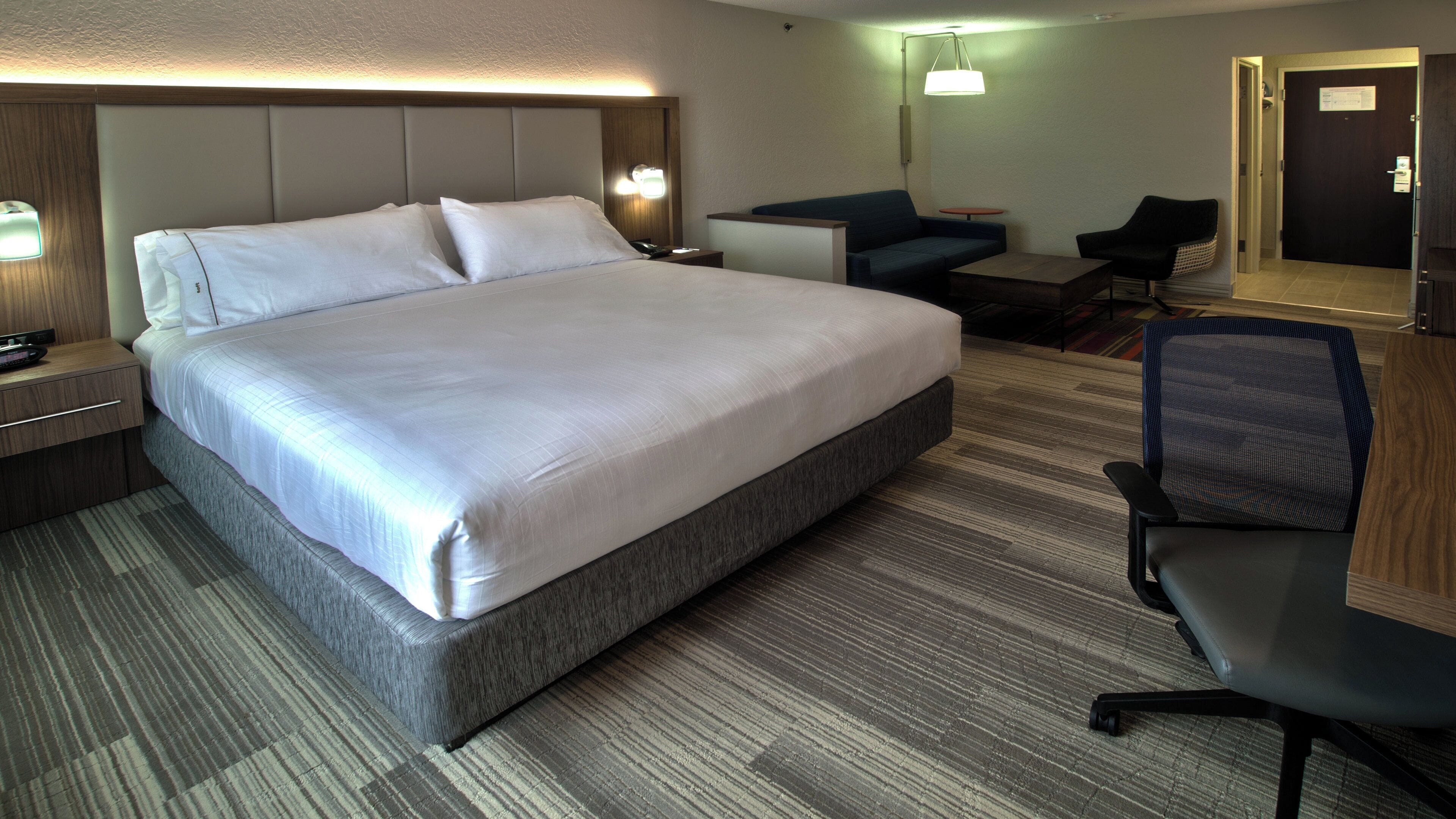 Une chambre d’hôtel avec un grand lit, un bureau, une chaise et une petite table.