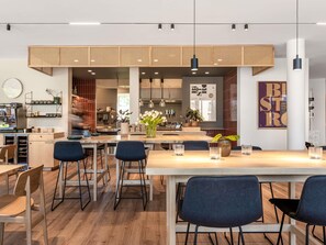 A modern kitchen with a central island, bar stools, and a dining table with chairs. - Oru Hub Hotel Tallinn - Handwritten Collection (Tallinn)