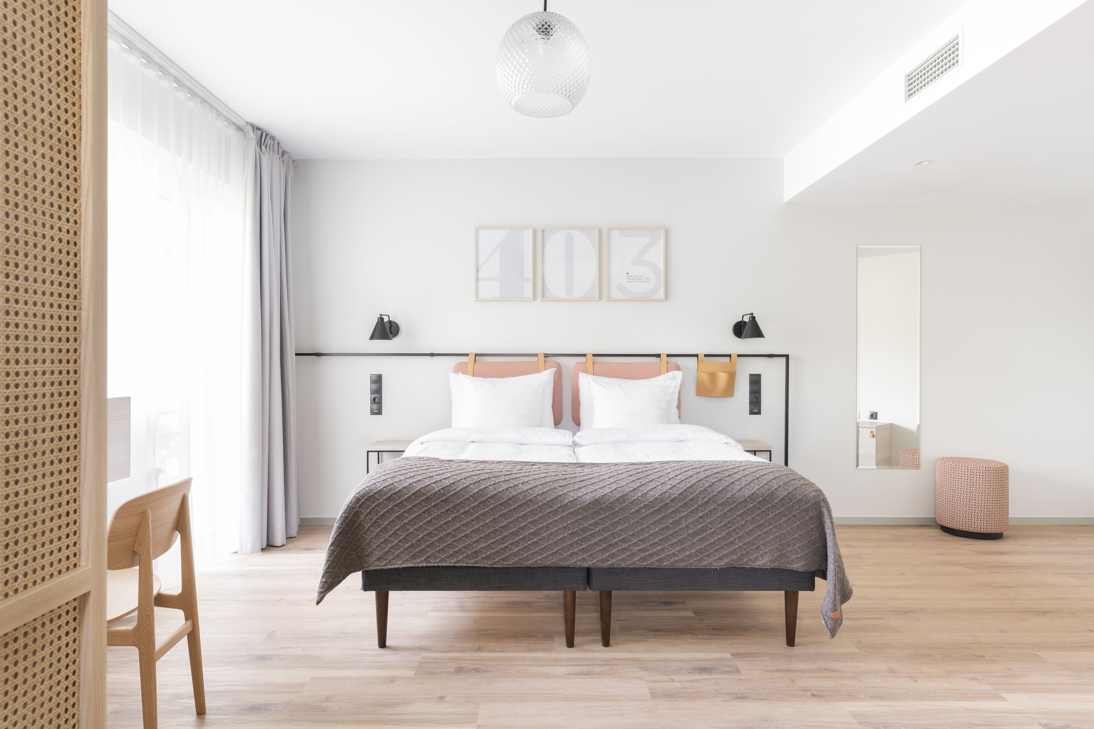 Ein modernes Schlafzimmer mit Bett, Nachttischen, einer Lampe, einem Wandbild und einem Fenster mit Vorhängen.