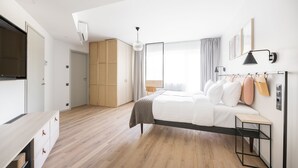 Un dormitorio moderno con cama, mesita de noche, armario y televisor.