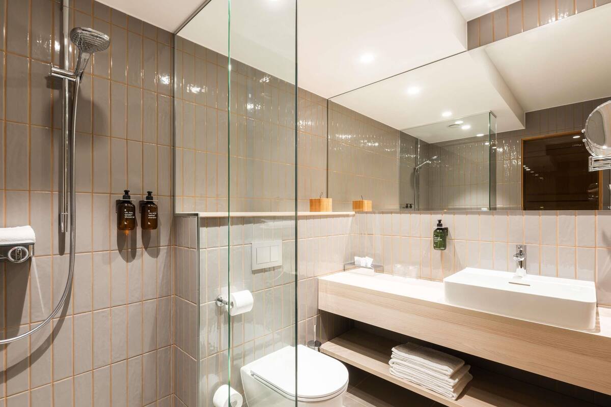 Une salle de bain moderne avec une douche à parois de verre, des toilettes, un lavabo et un miroir.