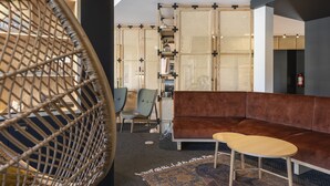 Un interior moderno con un sofá marrón, una silla de madera y un sillón colgante tejido.