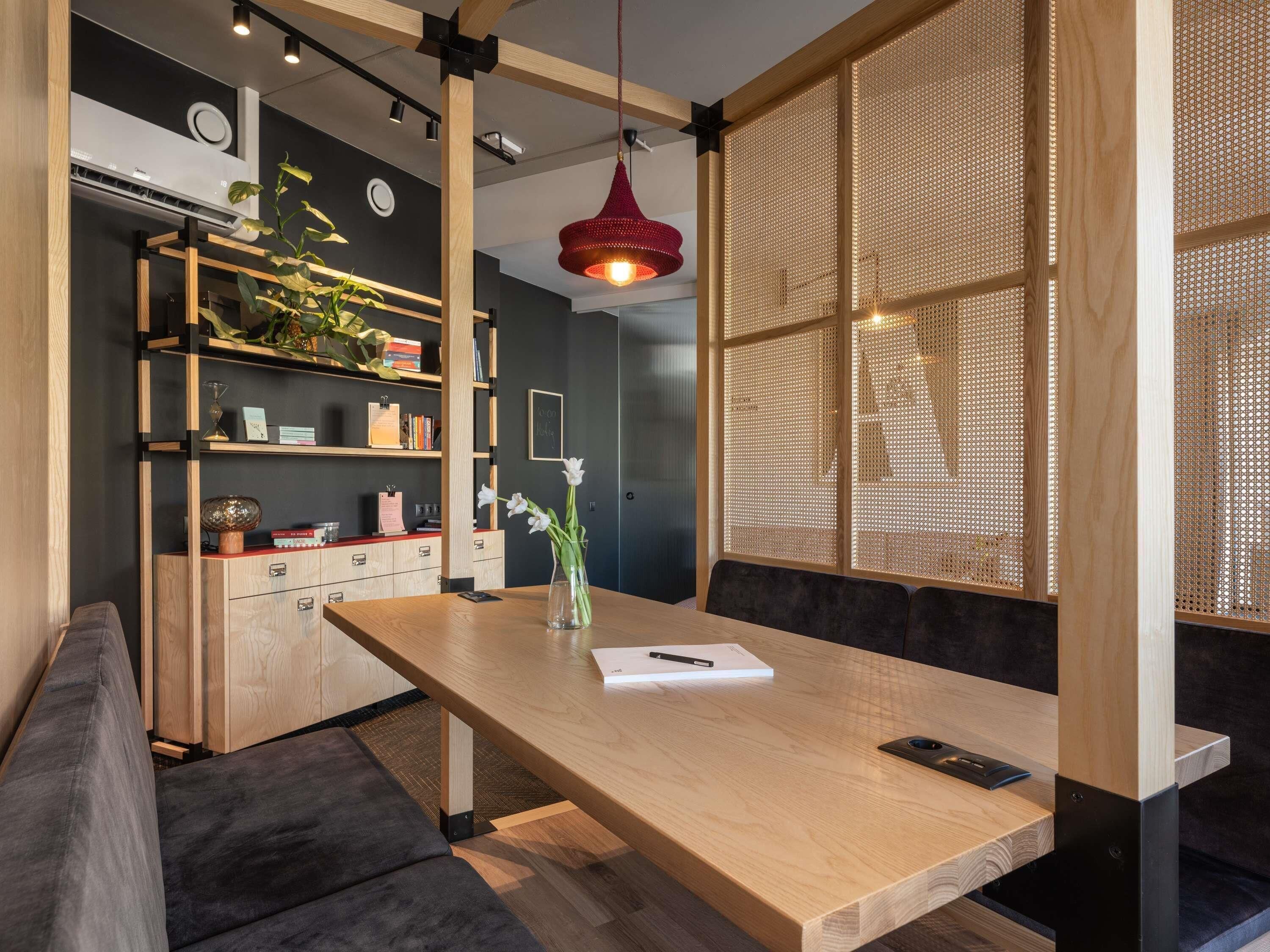 Un interior moderno con una mesa de madera, una lámpara colgante roja y una estantería.